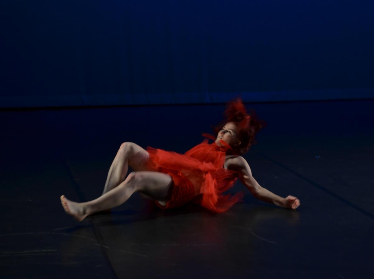 Sonsherée Giles, falling through the air, in a red dress, performing the Bach Cello Suites. Photo by: Carly Hoopes.