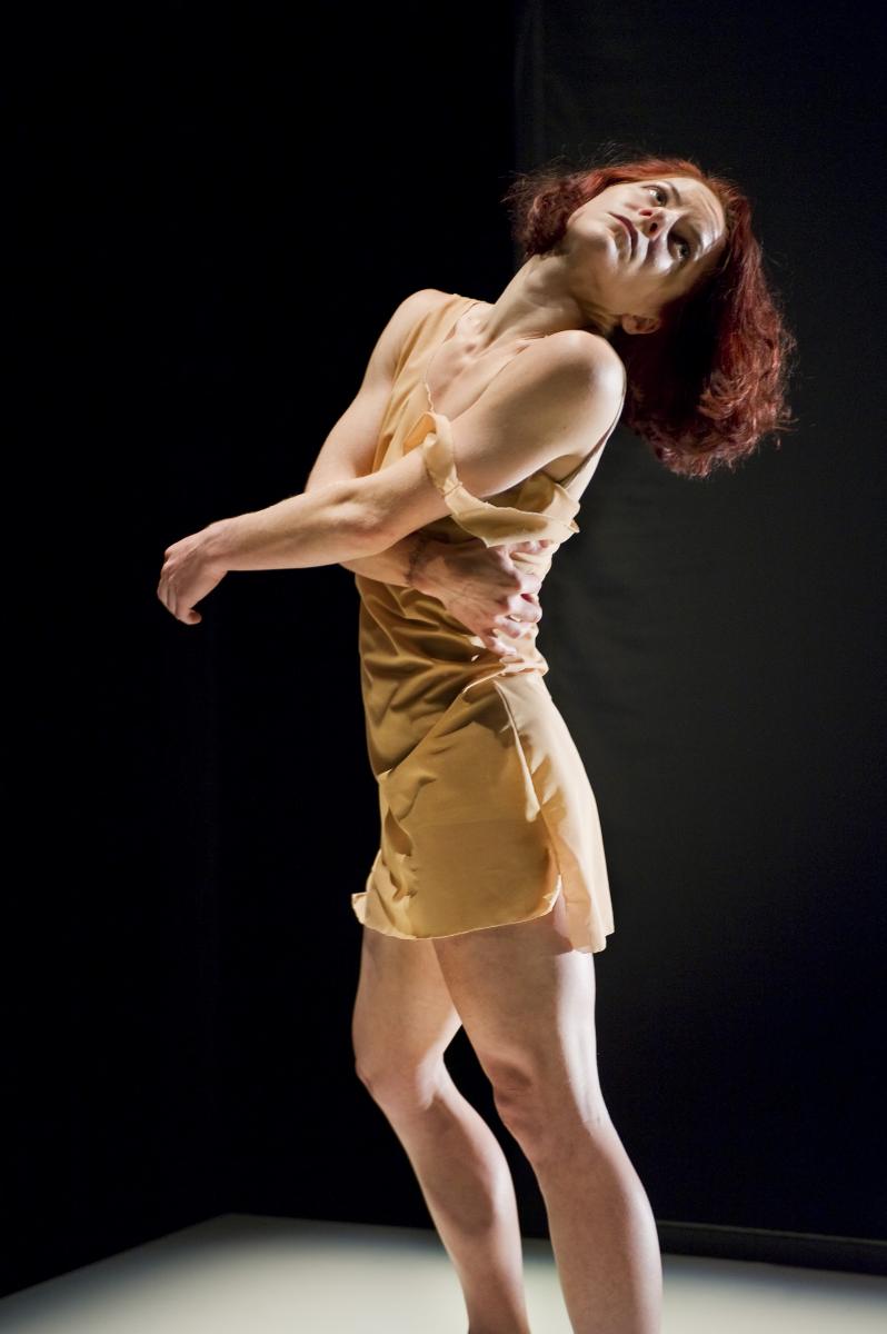 Sonsherée Giles, throwing her head back, wearing a tan colored dress, which was a costume in the production of "HyperReal."